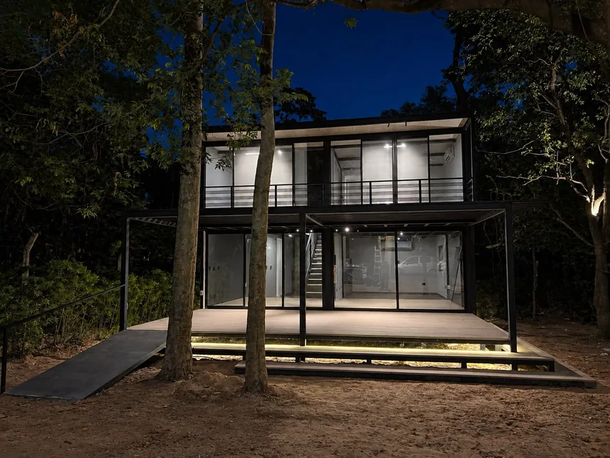 The Loft XL de dos plantas, iluminado de noche entre árboles